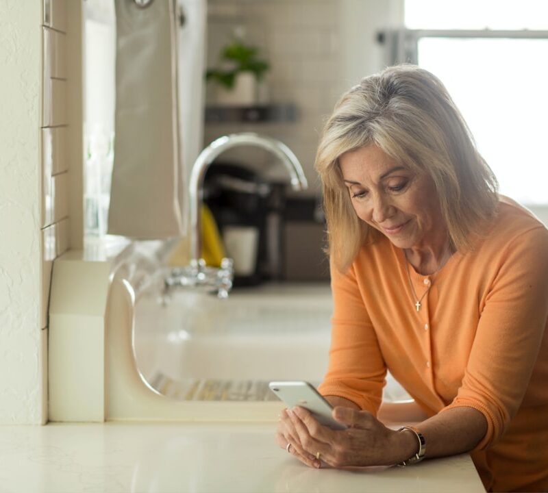 woman in orange long sleeve shirt using white smartphone